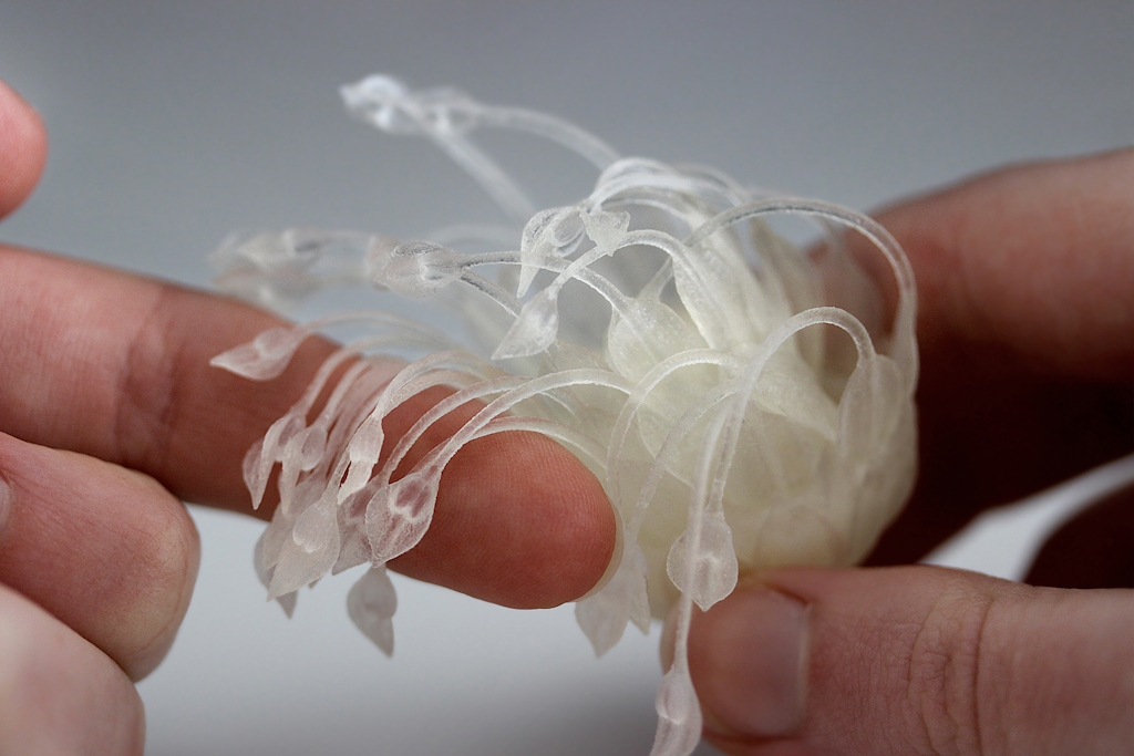 Human hand feeling the soft tendrils of a 3D printed flower.